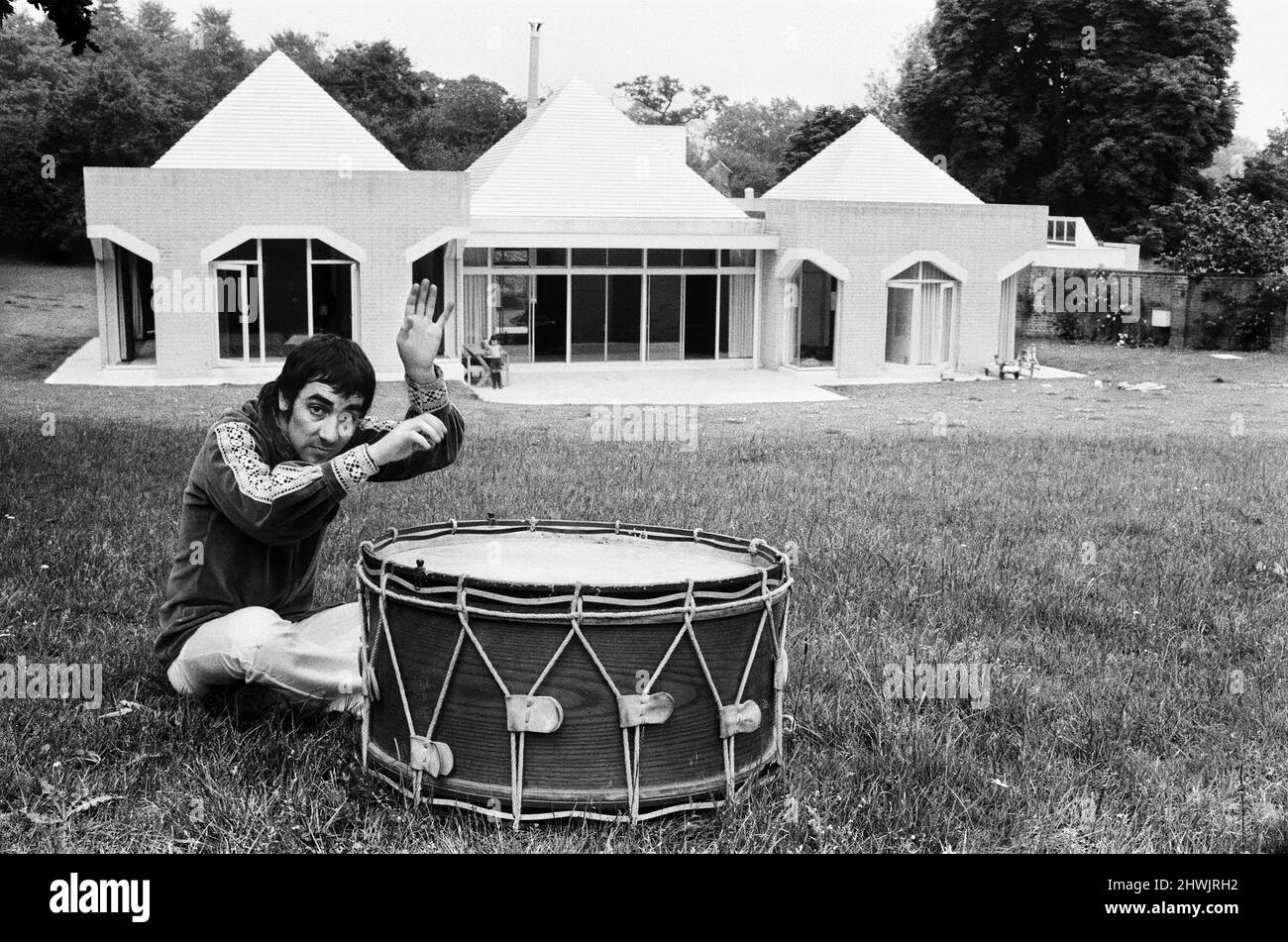 Keith Moon, batterista del gruppo rock dell'OMS, è stato raffigurato nella sua nuova casa del £60.000 chiamata Tara House a Chertsey, Surrey. La casa è nel mezzo di un campo a forma di piramidi con un pavimento ben sagomato nel soggiorno.Keith divertirsi con un vecchio tamburo che appartiene a sua figlia Mandy. 8th luglio 1971. Foto Stock