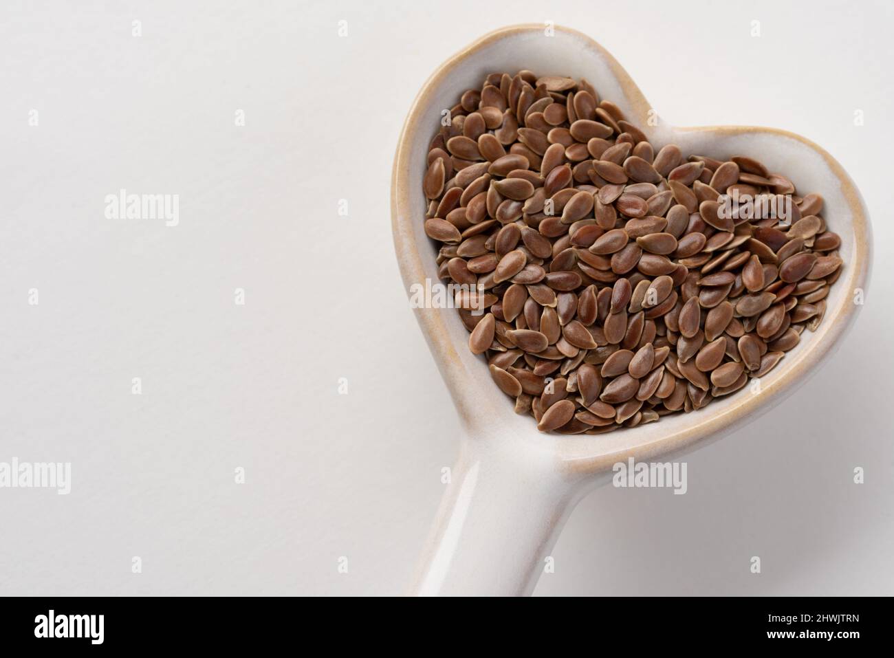 Marrone semi di lino su un cucchiaio a forma di cuore Foto Stock