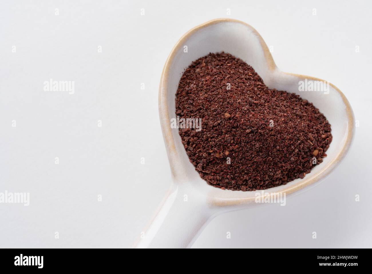 Ground Sumac su un cucchiaio a forma di cuore Foto Stock