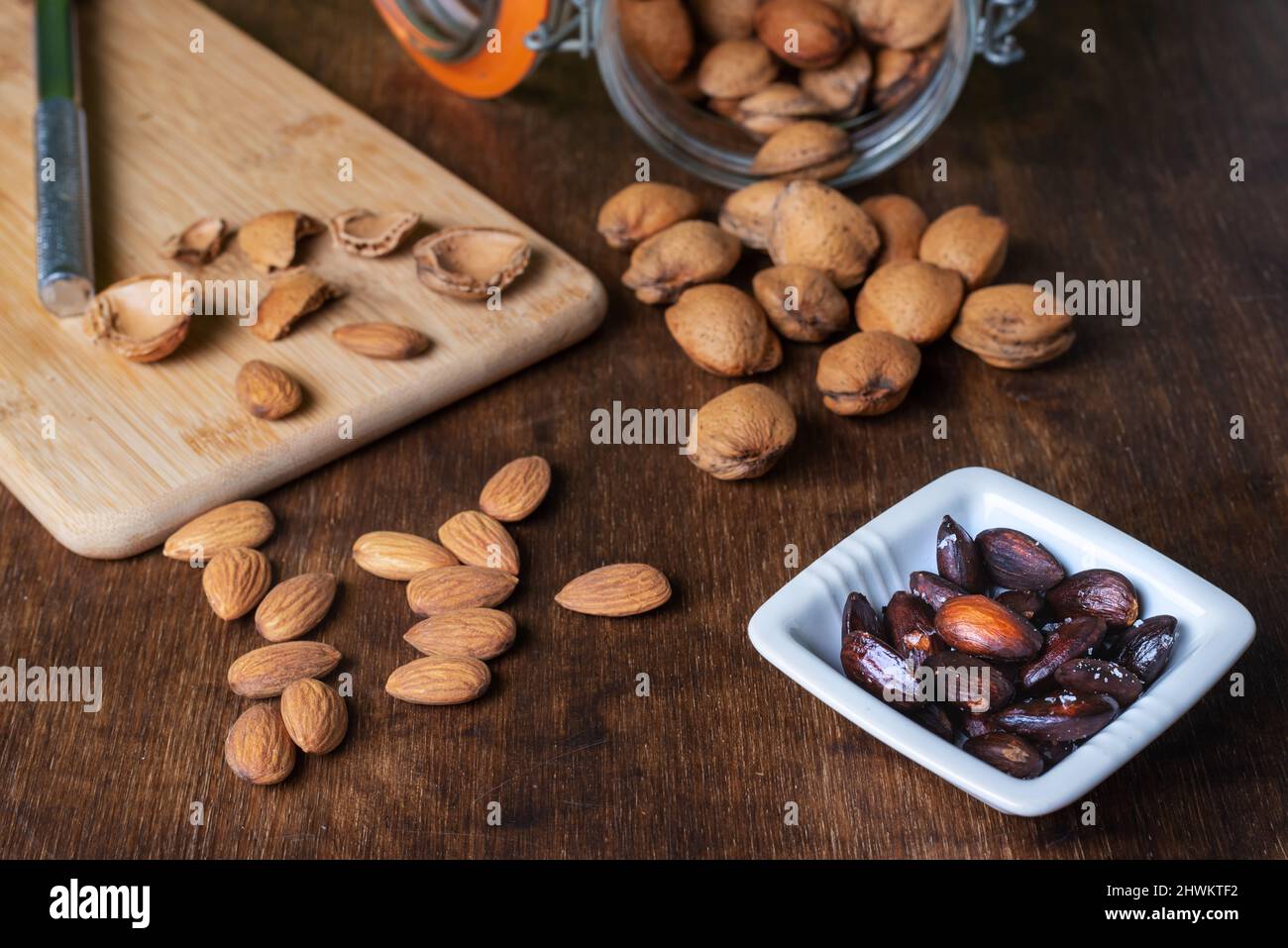 Mandorle, semi e conchiglie di mandorle accanto ad un vaso con mandorle fritte. Foto Stock