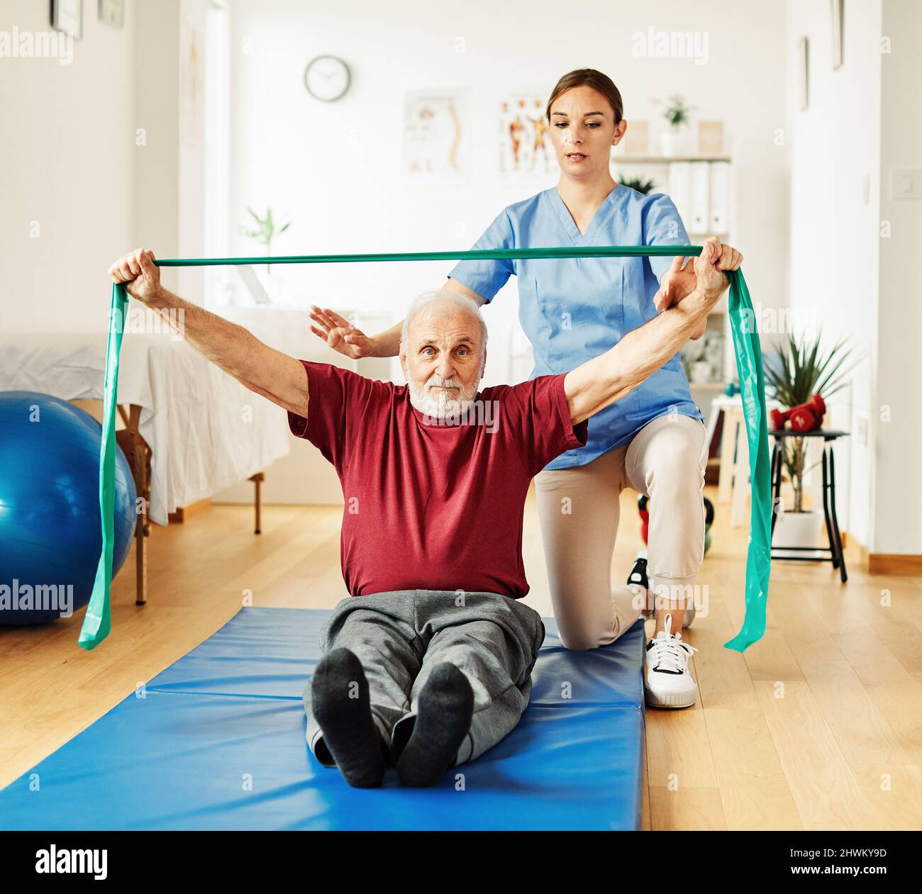 infermiera medico cura senior esercizio fisico terapia esercizio aiuto assistenza pensione casa fisioterapia strech band clinica terapista anziano uomo Foto Stock