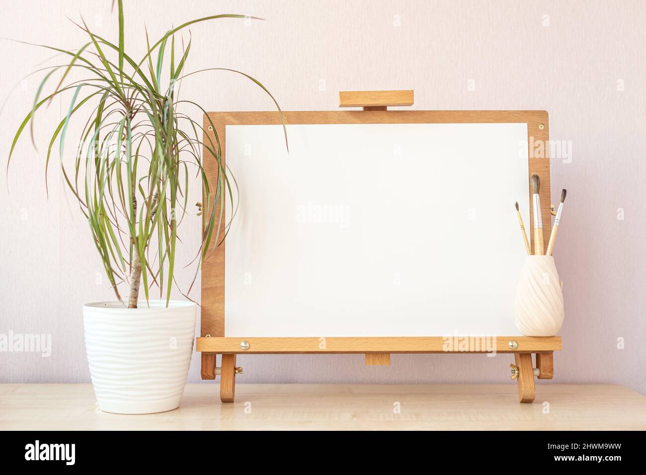 Carta bianca bianca bianca per la pittura su cavalletto di legno sul tavolo dello studio di casa Foto Stock