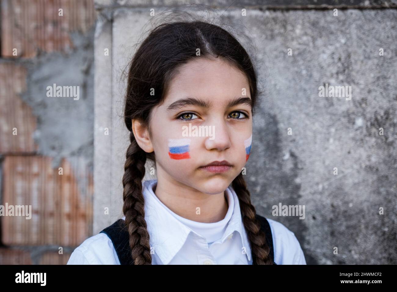 Ritratto di una bambina triste con colori russi sul viso. Concetto di pace e protezione per i bambini Foto Stock