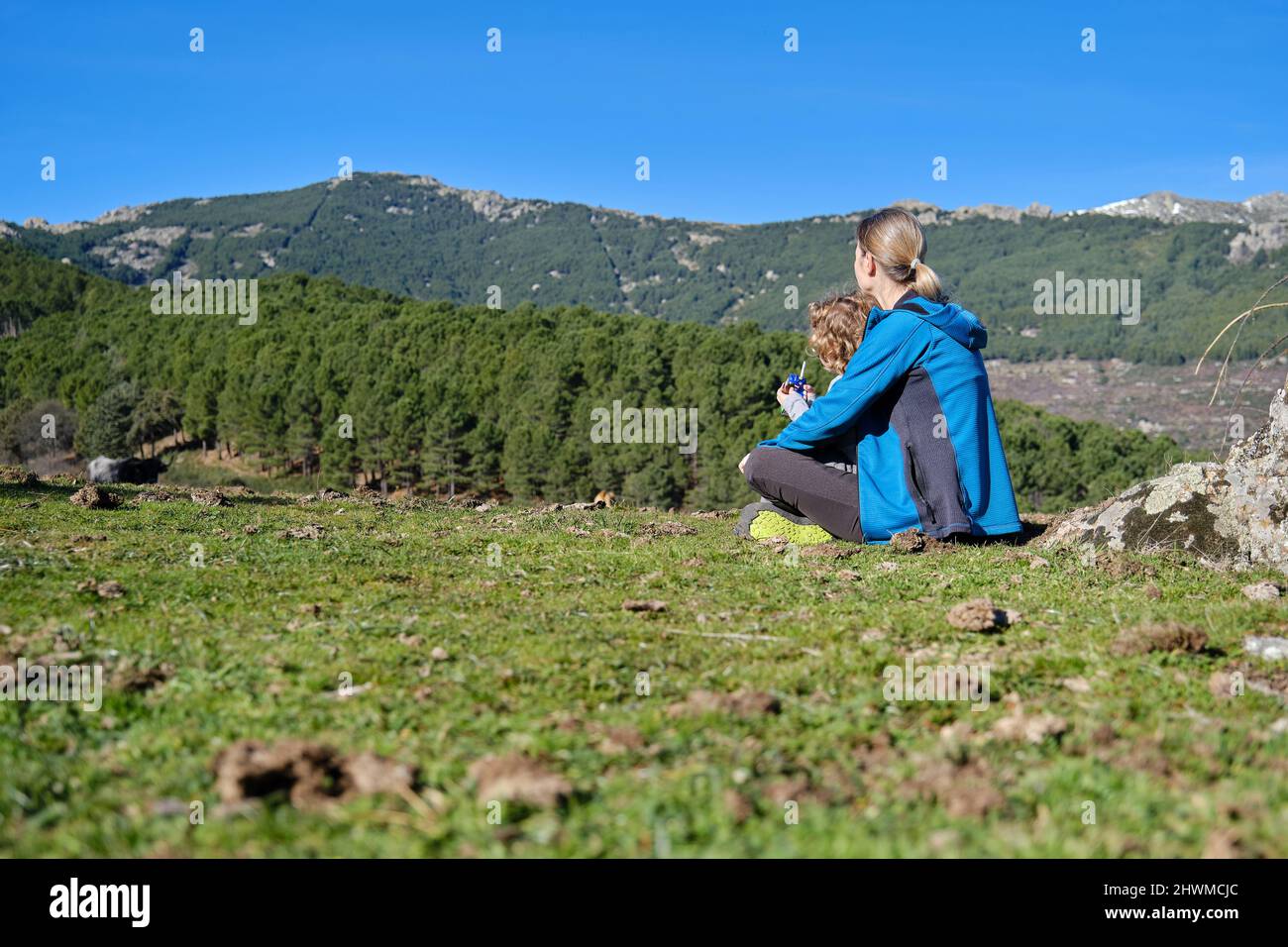 Un bambino adorabile che beve un cartone di latte attraverso una paglia in natura con la madre Foto Stock