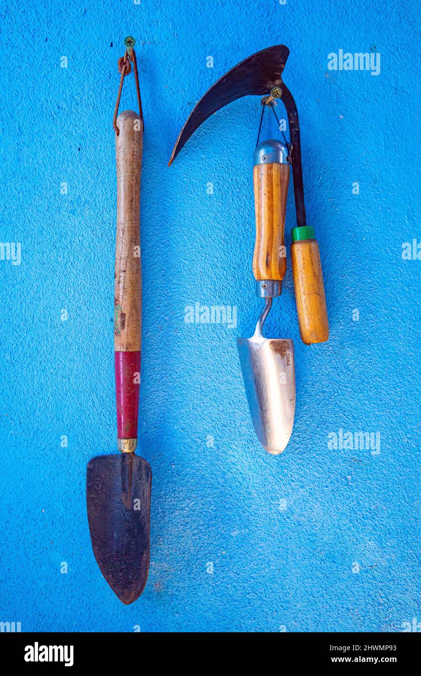 Gli utensili a tre mani più utilizzati per il giardinaggio dei contenitori sono appesi all'esterno per un uso rapido. Foto Stock