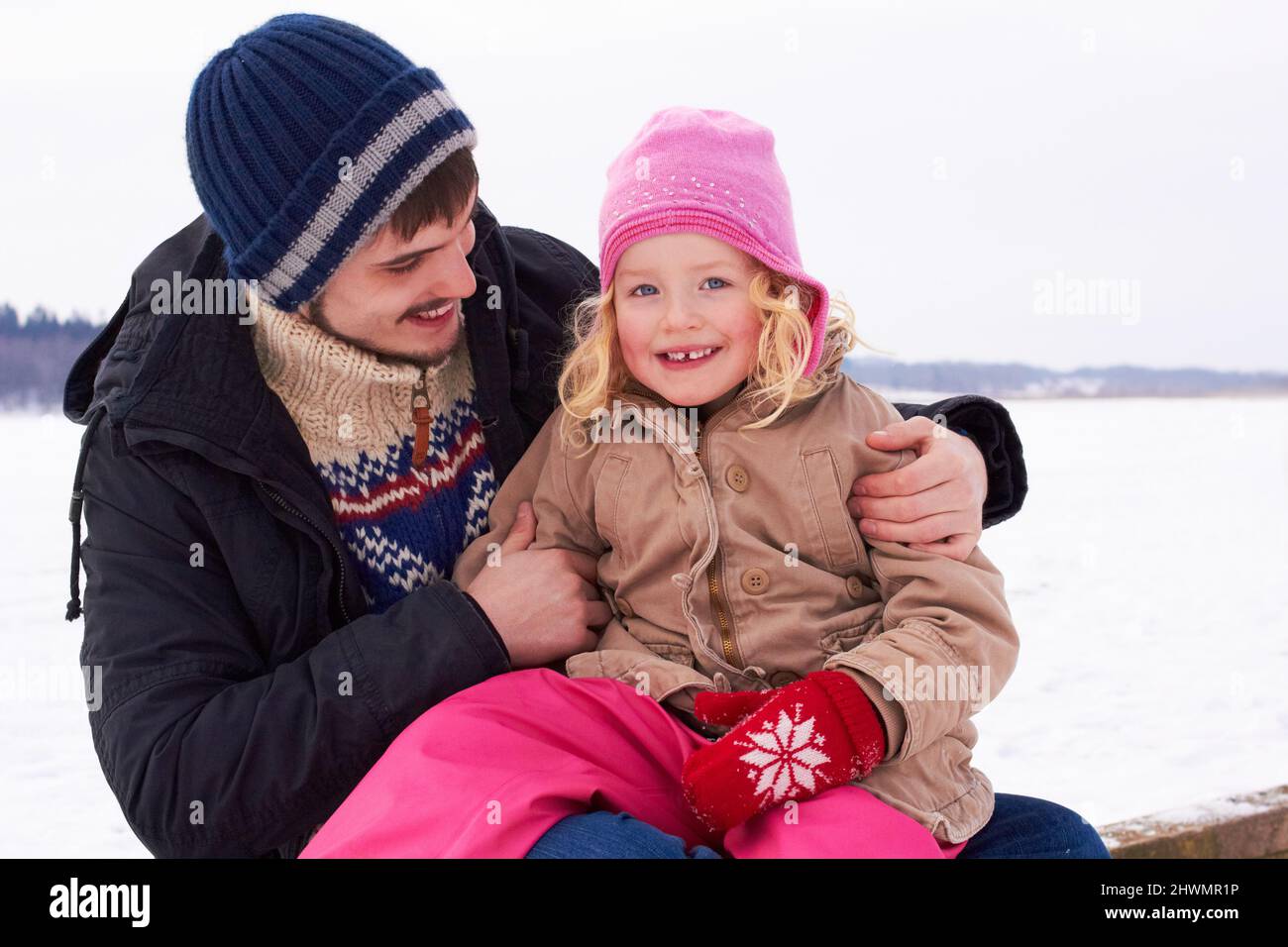 Ama trascorrere il tempo con mio padre. Bambina seduta felicemente sui suoi padri lap fuori in un giorno croccante inverni. Foto Stock