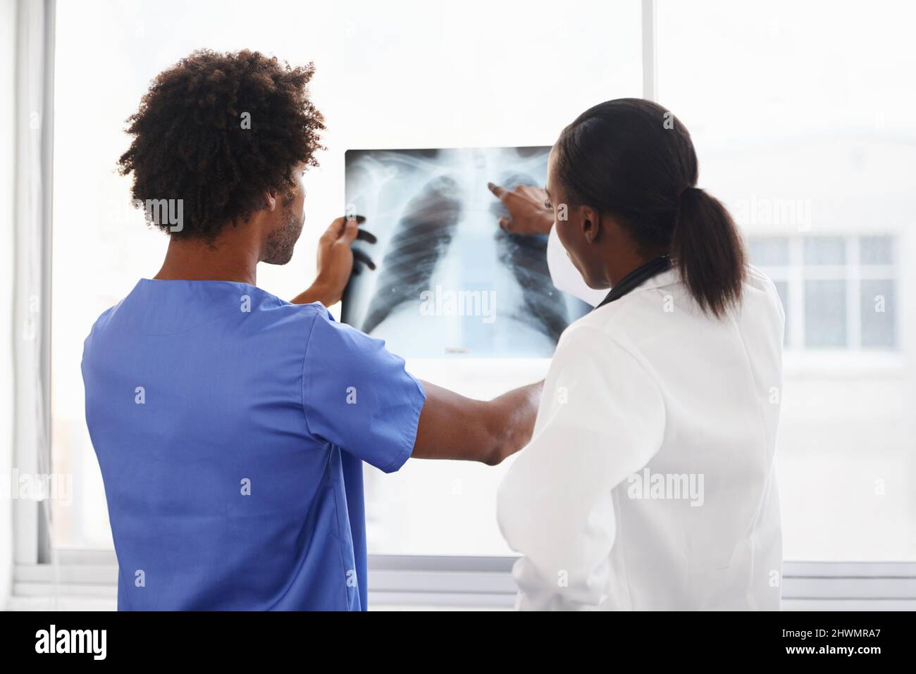 I raggi X approfondimenti nel corpo. Shot di un medico femminile e di un'infermiera maschile che studia i raggi X. Foto Stock