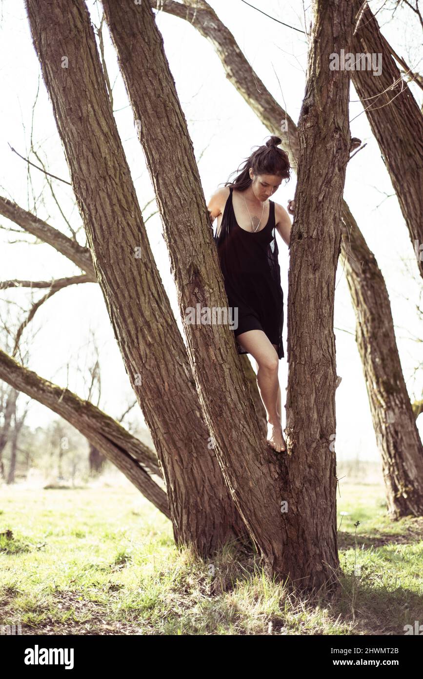 donna naturale in abito nero a piedi nudi in albero e sole in germania Foto Stock