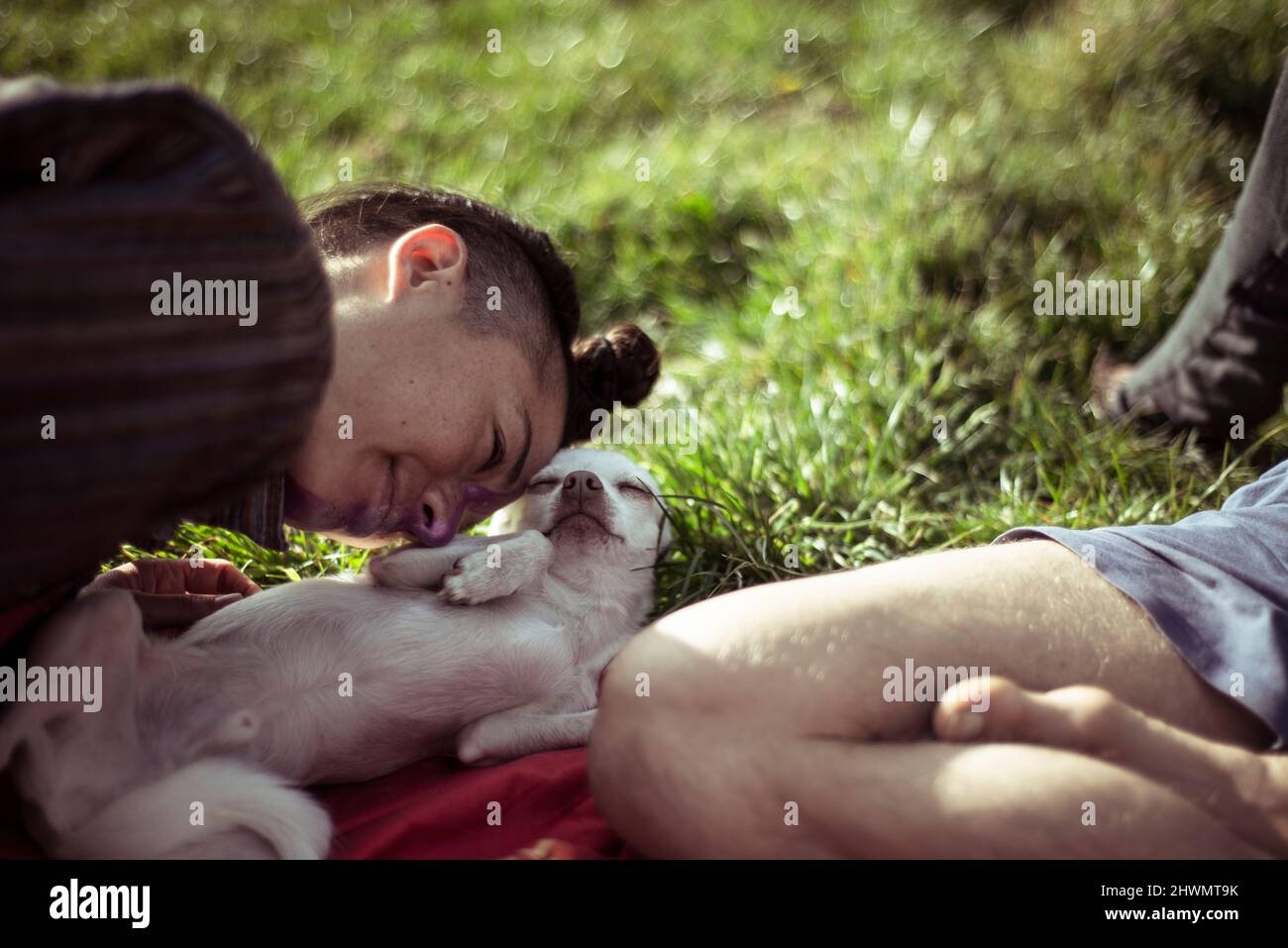 Persona androgina coccolare con un piccolo cucciolo in estate pic-nic Foto Stock