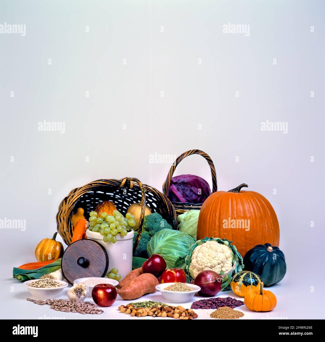 Cesti di frutta, verdura, grani, e noci disposti in una cascata di colore evidenzia zucche, cavolo, cavolfiore, broccoli, uva, c Foto Stock
