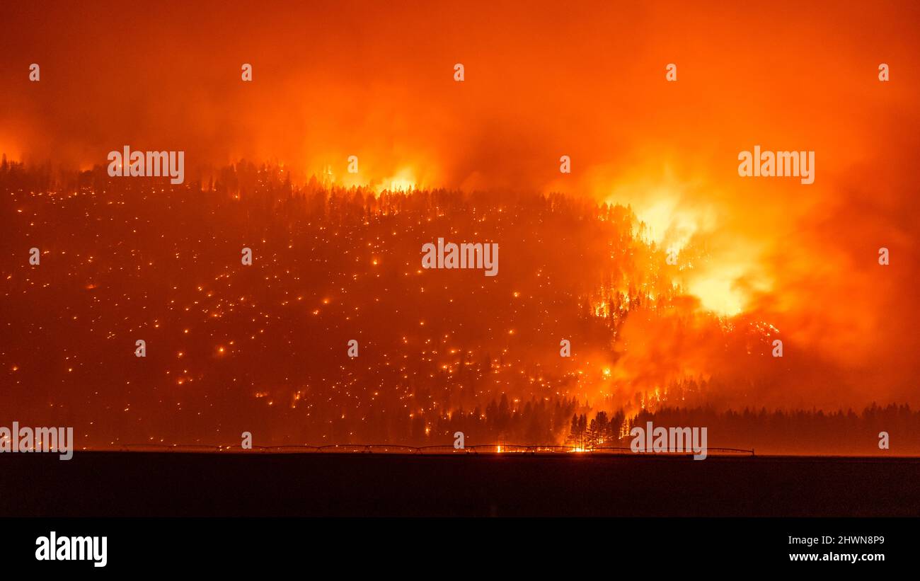 Il fuoco selvatico della California brucia lungo una cresta vicino ai terreni agricoli Foto Stock