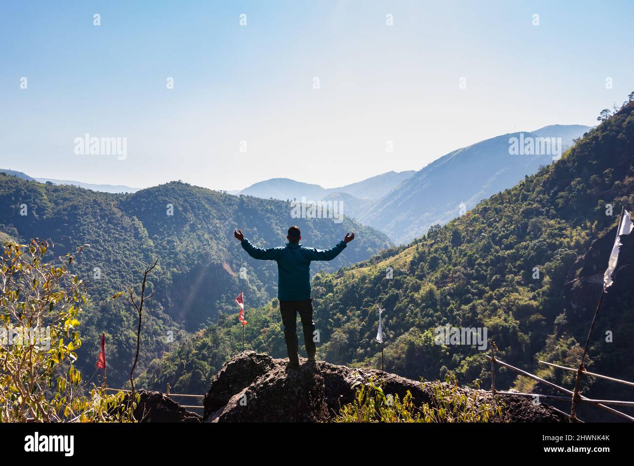 L'uomo giovane isolato in cima alla montagna con foreste verdi e il cielo blu nebuloso al mattino da un'immagine piatta è scattato al Mawryngkhang Trek meghalaya indi Foto Stock