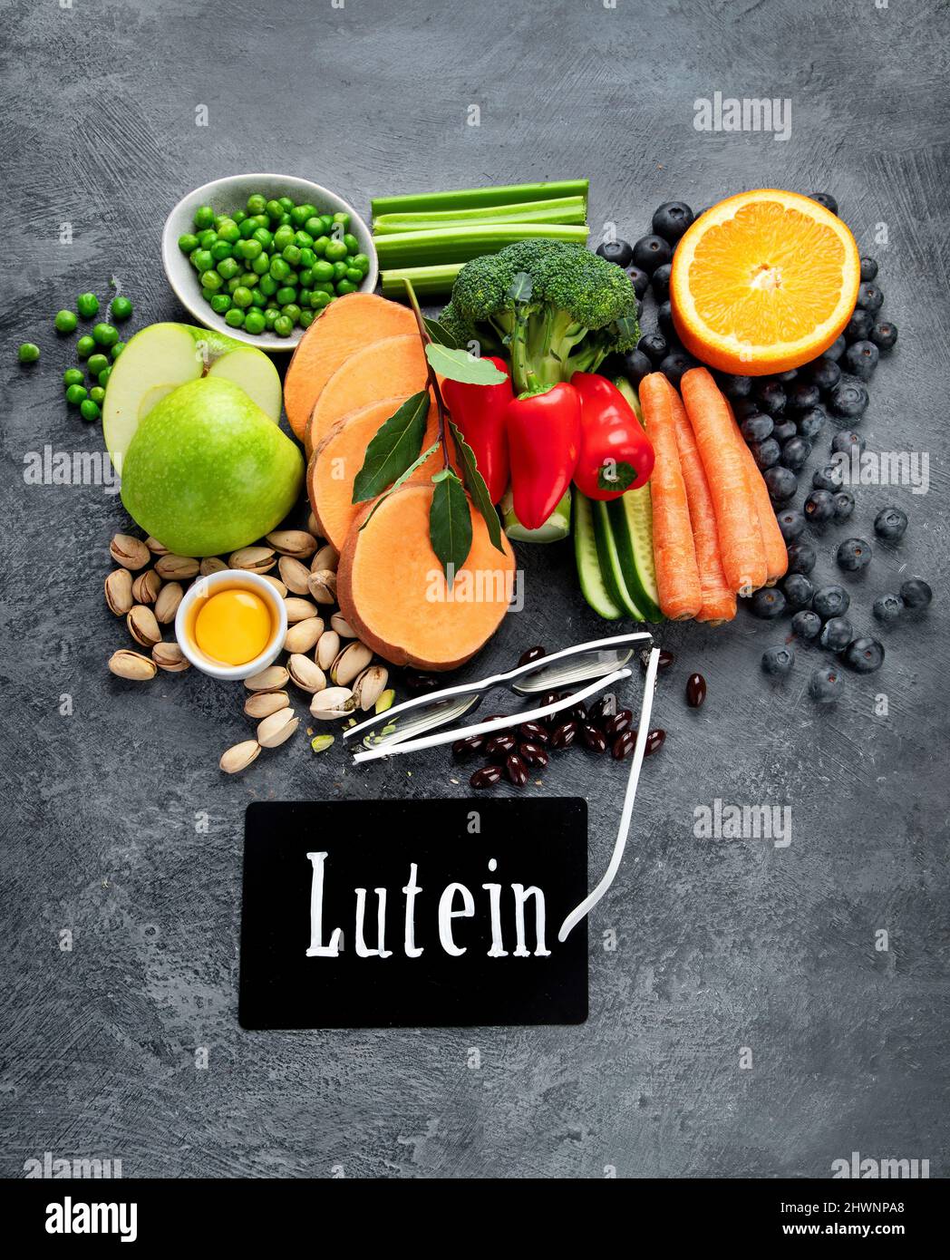 Alimenti alti in luteina su sfondo scuro. Cibo per occhi sani. Alto in antiossidanti, minerali e vitamine. Vista dall'alto, disposizione piatta, spazio di copia Foto Stock