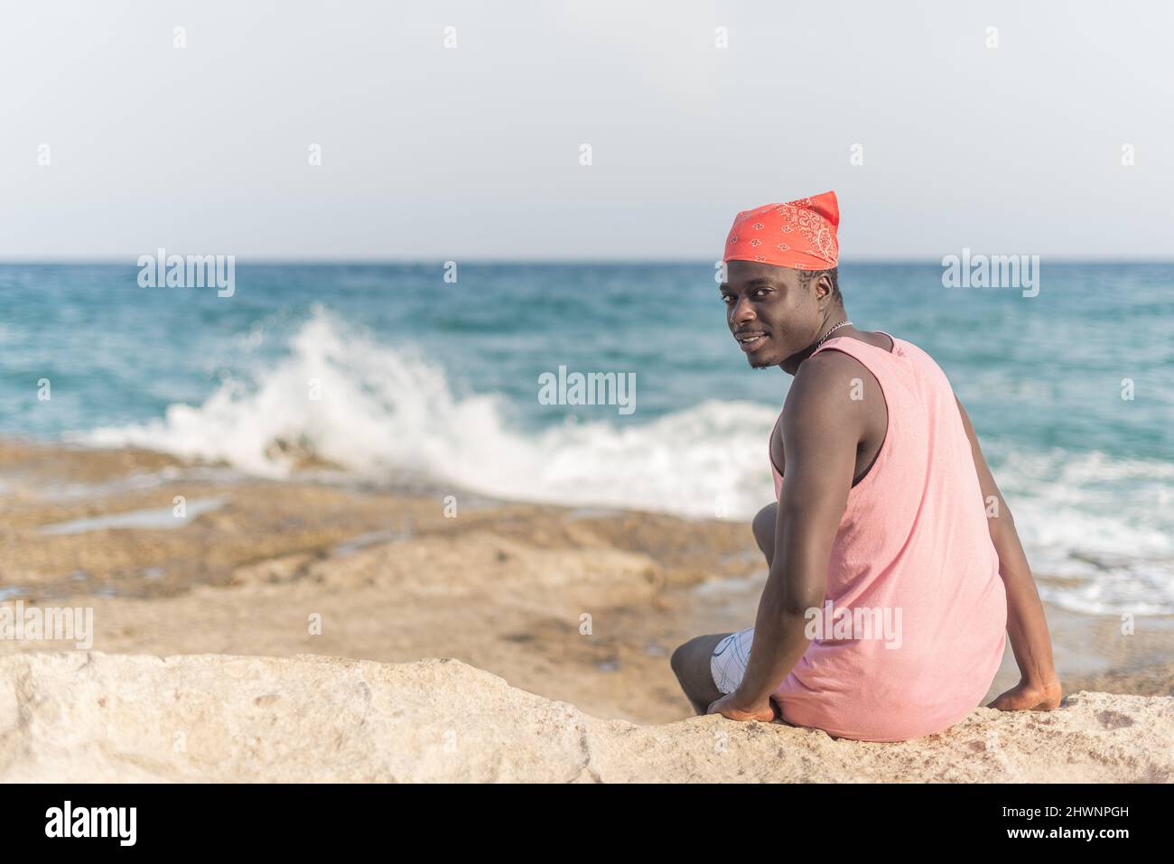 uomo nero seduto sulla sabbia con la testa girata Foto Stock