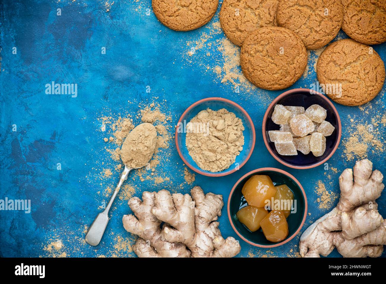 Zenzero in polvere, radice di zenzero, zenzero cristallino e zenzero a gambo con biscotti fatti in casa di zenzero su sfondo blu Foto Stock