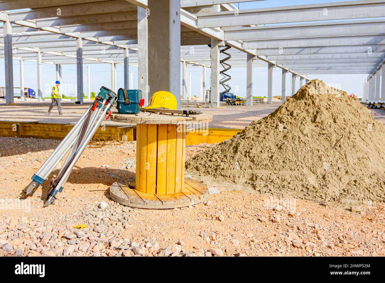 Le attrezzature per il rilevamento topografico imballate, lo strumento in una scatola di plastica e un cavalletto, vengono poste su una bobina di legno in cantiere. Foto Stock