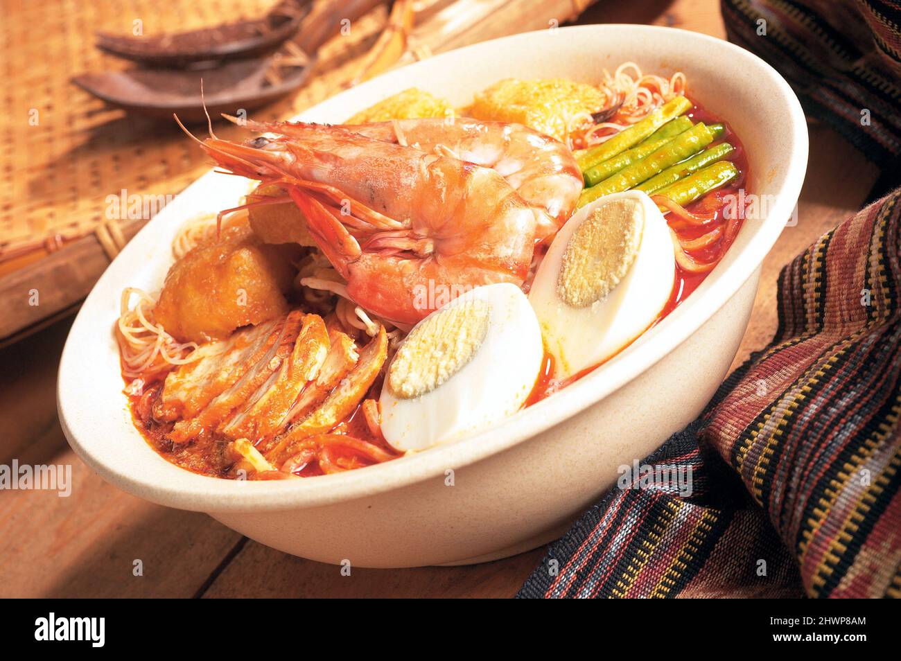 Laksa al curry in stile asiatico con gamberi, uova sode, polpe di tofu, pancia di maiale arrosto e verdure Foto Stock