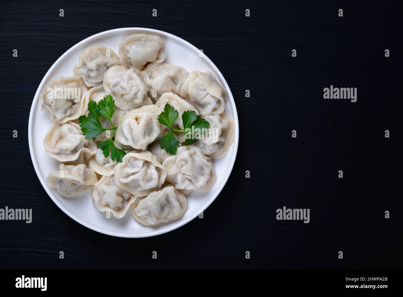 Tradizionale pelmeni russo, ravioli, gnocchi con carne su sfondo nero. Foto Stock