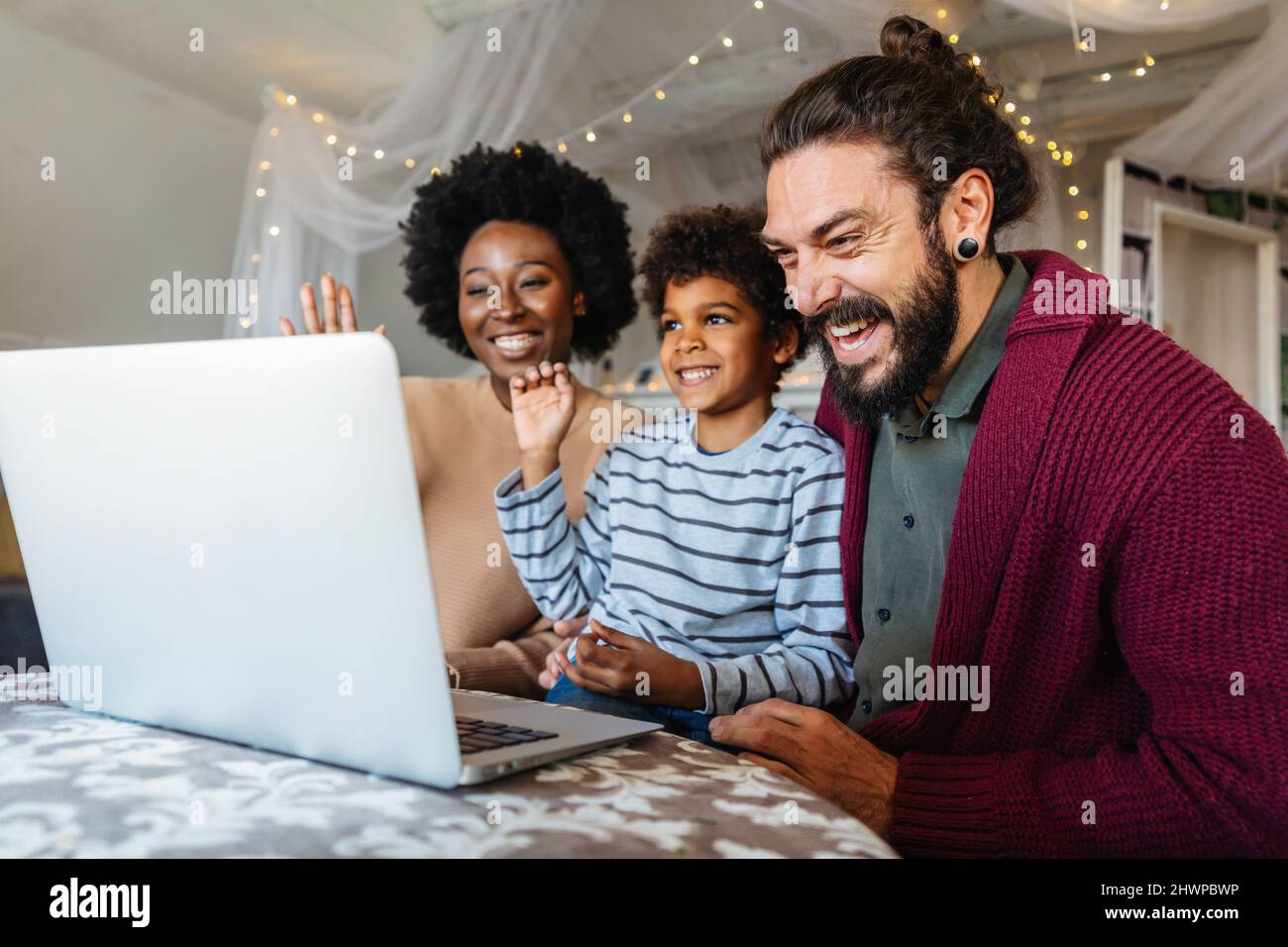 Giovane famiglia allegra multietnica che parla con i parenti in video chat Foto Stock