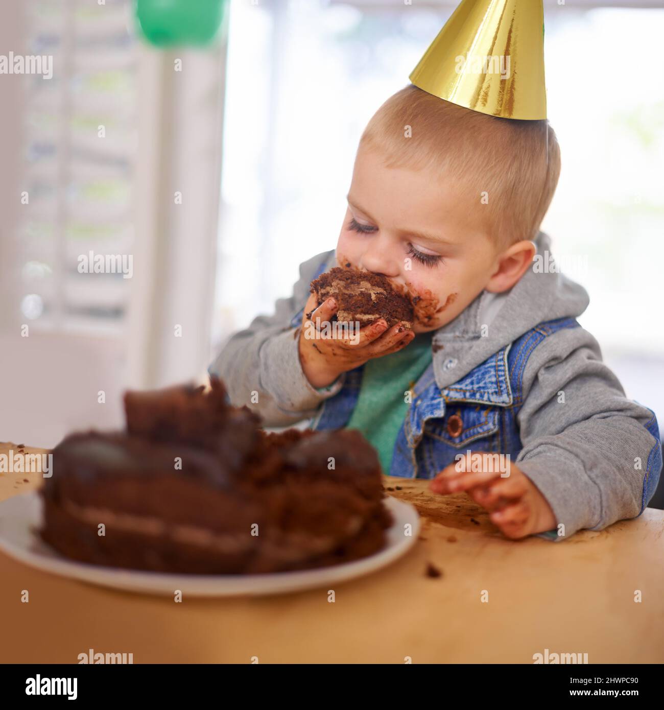 Che lo lasciò solo con la torta. Scatto corto di un ragazzo che mangia la sua torta di compleanno prima della festa. Foto Stock