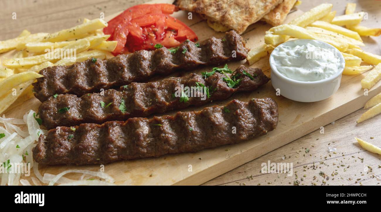 Shish kebab, doner souvlaki, arrostito di carne tradizionale Street food. Piatto etnico, pita pane, tzatziki yogurt patate e cipolla su tavola di legno, primo piano Foto Stock