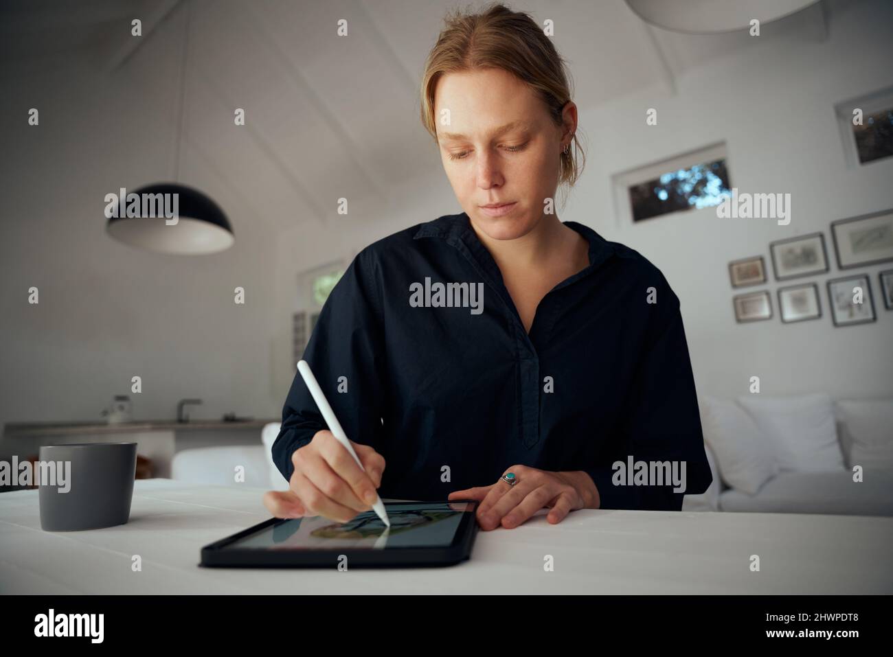 Fashion designer caucasica femminile che lavora da casa per la progettazione di capi di abbigliamento su tablet digitale Foto Stock