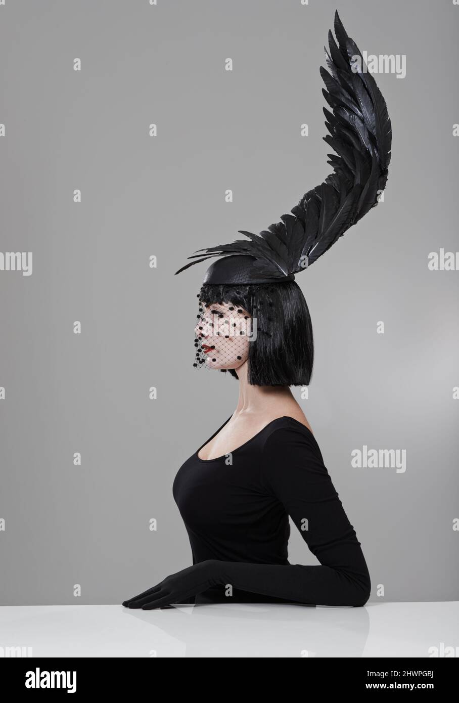 Alle nuove vette della moda. Scatto di una giovane donna in un headpiece a forma di ala seduto in uno studio. Foto Stock