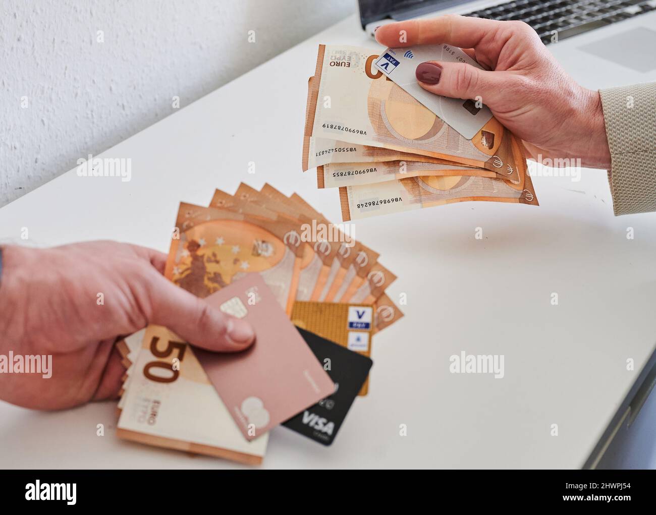 ILLUSTRAZIONE - 05 marzo 2022, Berlín;: La mano di un uomo (sinistra) ·50 banconote e diverse carte di credito, mentre la mano di una donna detiene meno banconote e una carta di debito. Le donne tedesche hanno continuato a guadagnare meno degli uomini nel 2021. Secondo l'Ufficio federale di statistica, il cosiddetto divario retributivo tra i sessi è rimasto invariato rispetto all'anno precedente, attestandosi in media al 18%. Foto: Annette Riedl/dpa Foto Stock