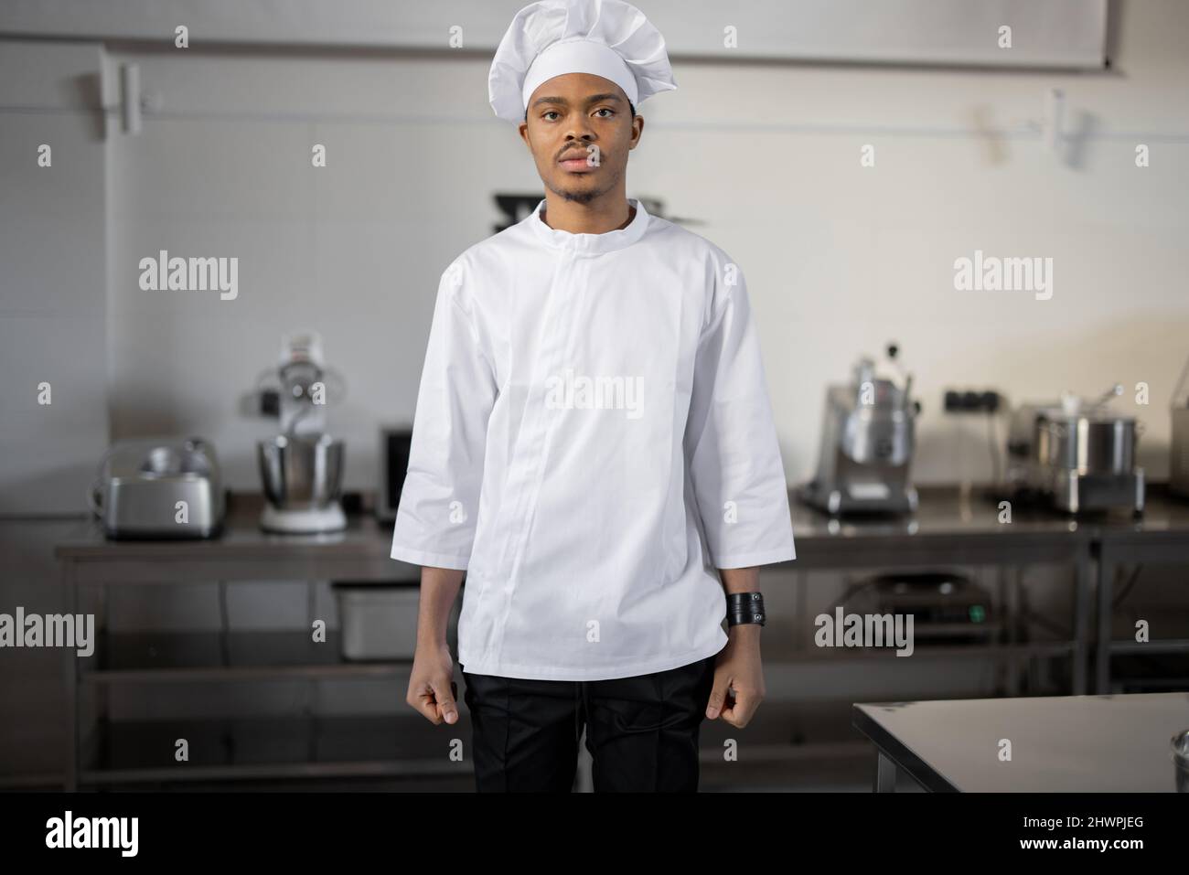 Ritratto di un bel chef latino in piedi uniforme in cucina professionale ristorante. Lavoratori al concetto di lavoro Foto Stock