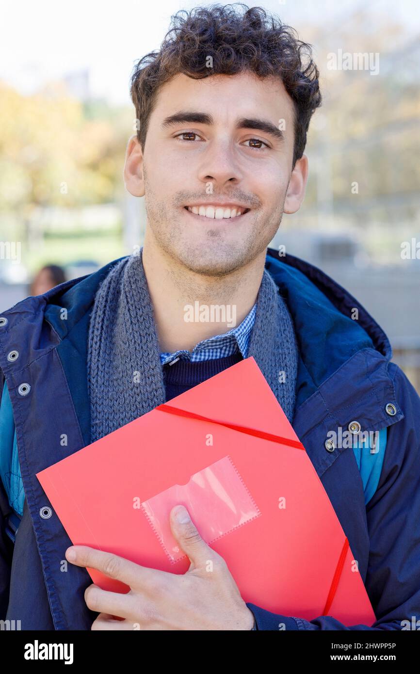 Uomo sorridente con lima rossa al campus Foto Stock