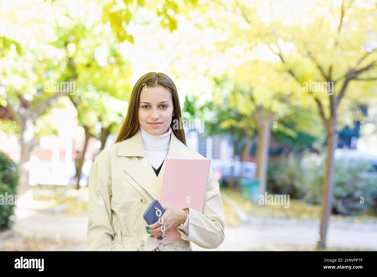 Giovane studente con smartphone e libro nel campus Foto Stock