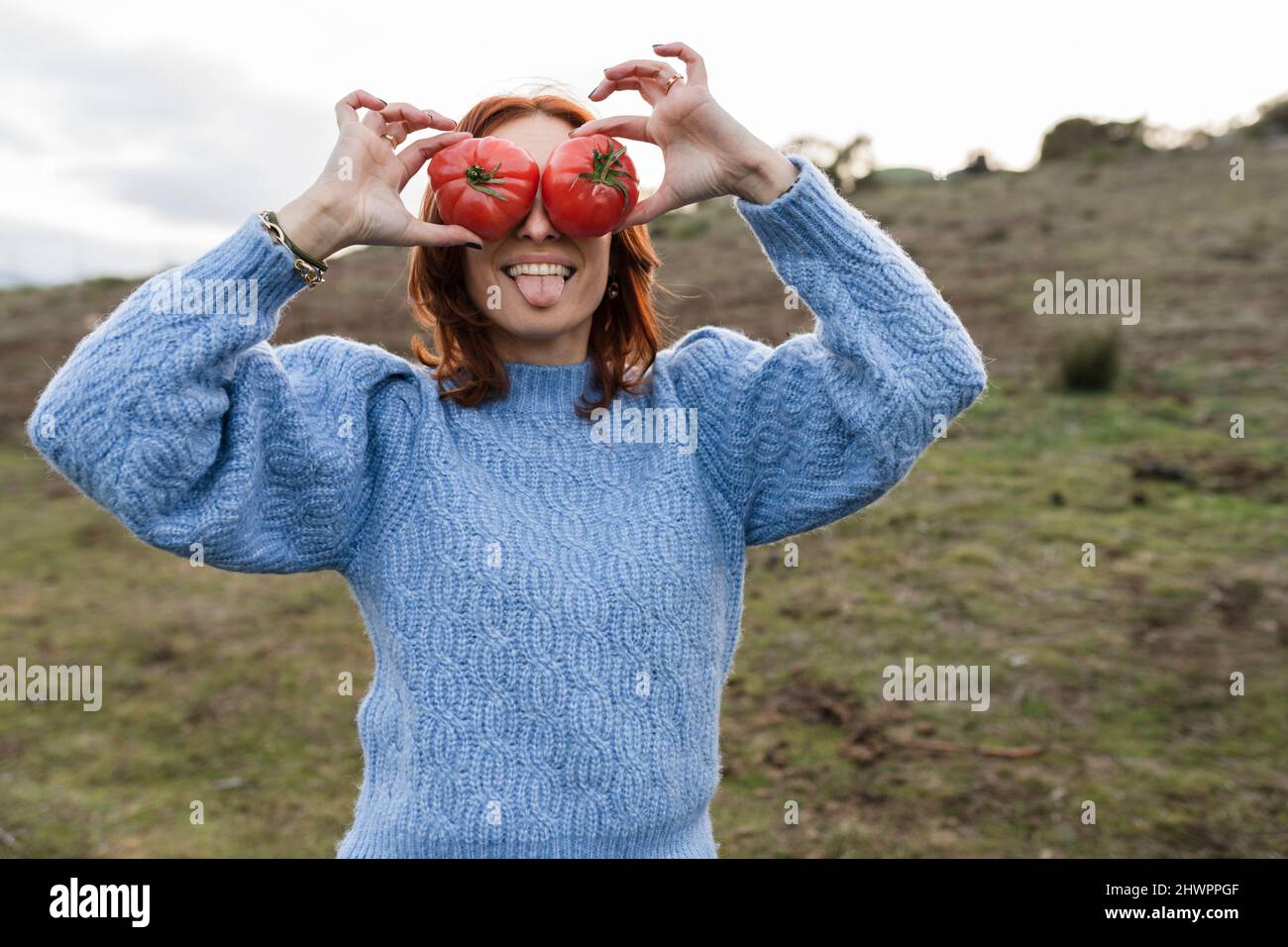 Donna che attacca la lingua e ricopre gli occhi con peperone rosso Foto Stock