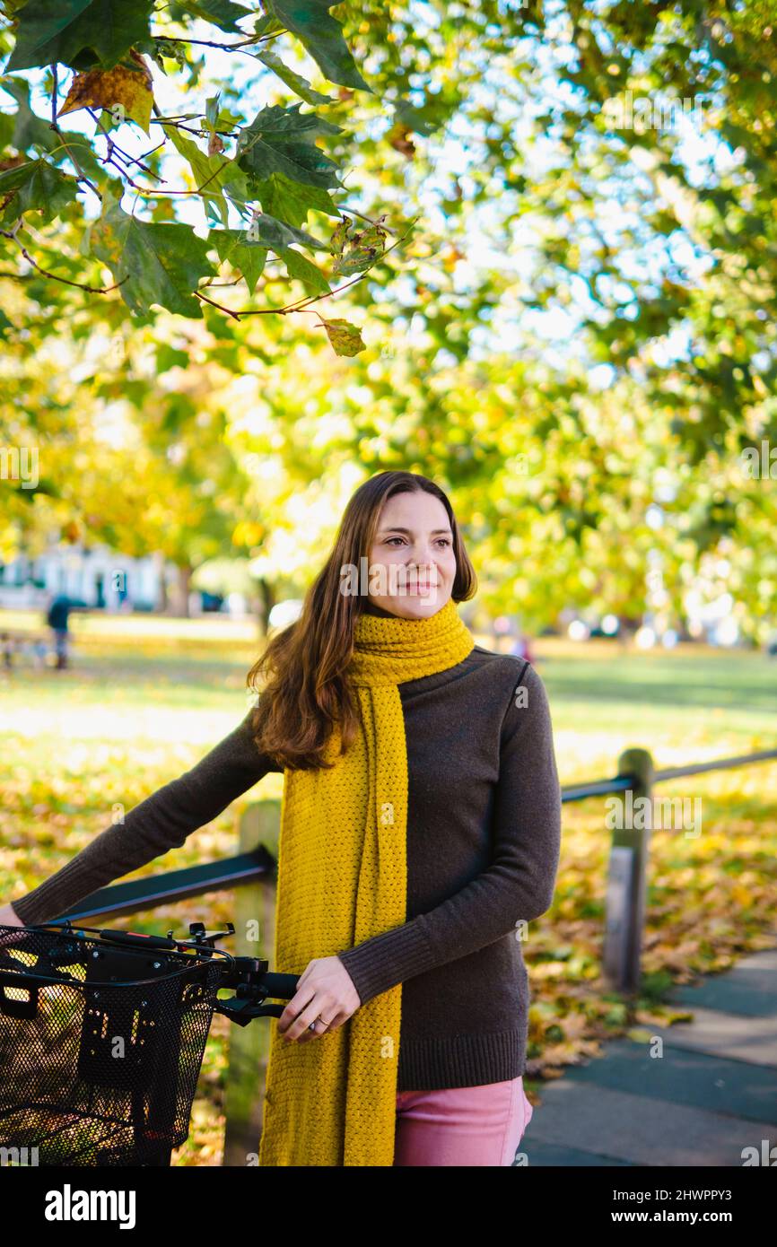 Bella donna che ruota in bicicletta al parco autunnale Foto Stock