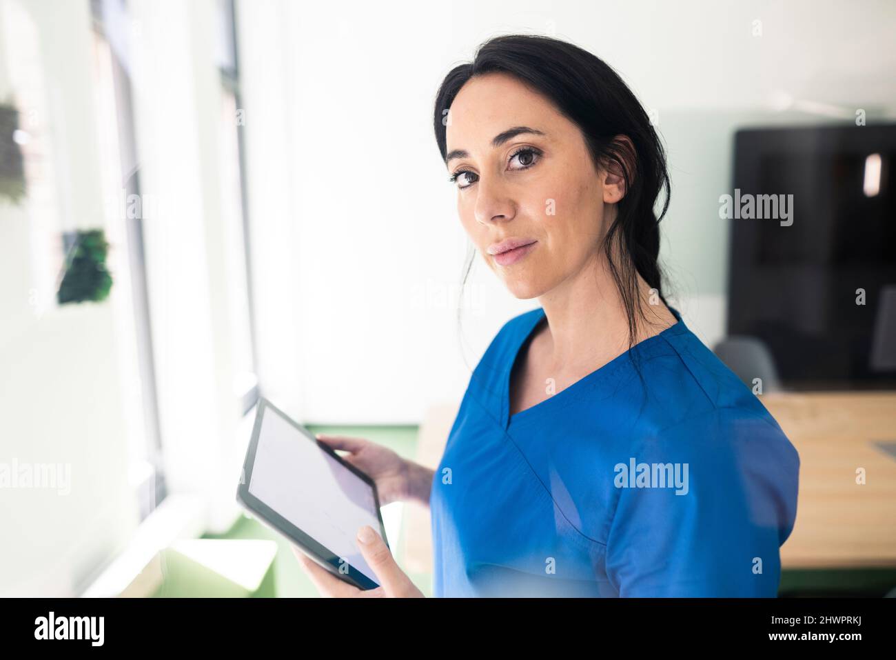 Infermiera in scrub medico blu che tiene il PC tablet in ospedale Foto Stock