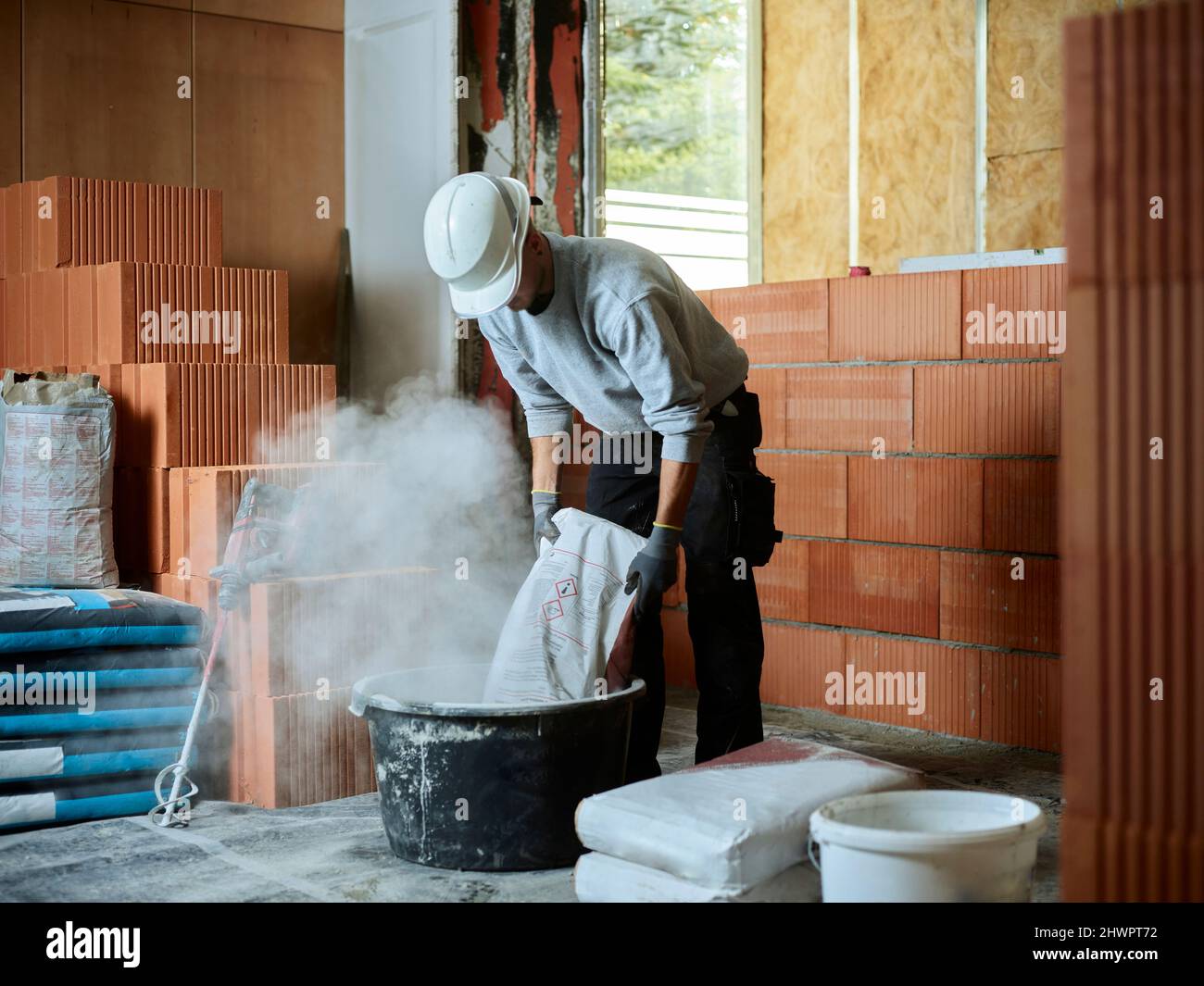 Muratore che mette cemento in vasca al luogo di costruzione Foto Stock