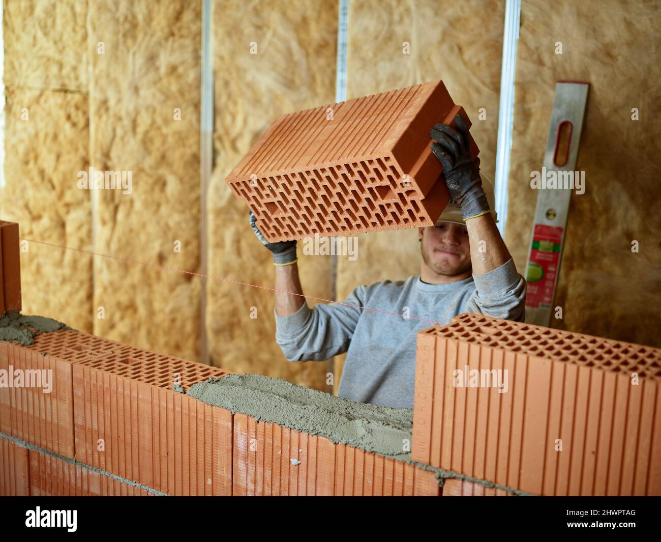 Muratore che tiene la lastra di mattone che lavora al luogo di costruzione Foto Stock