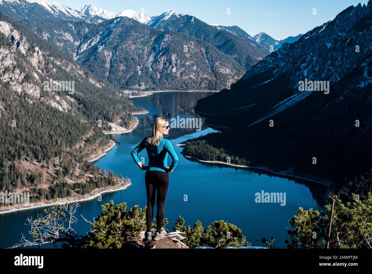 Donna con le mani sul fianco guardando la vista da Tauern sopra il lago Plansee, Alpi Ammergau, Reutte, Tirolo, Austria Foto Stock