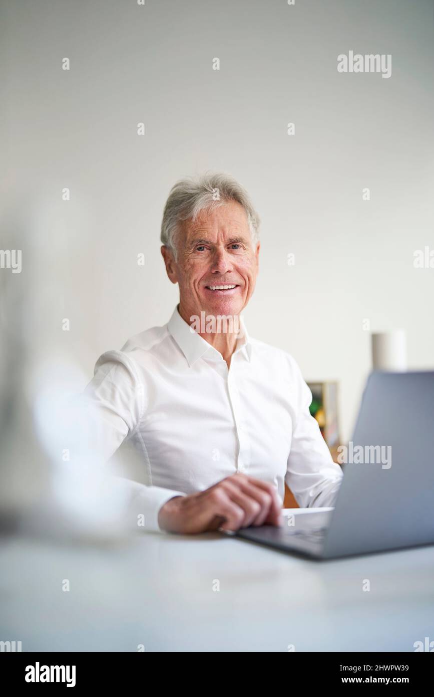 Uomo d'affari con computer portatile alla scrivania in studio Foto Stock