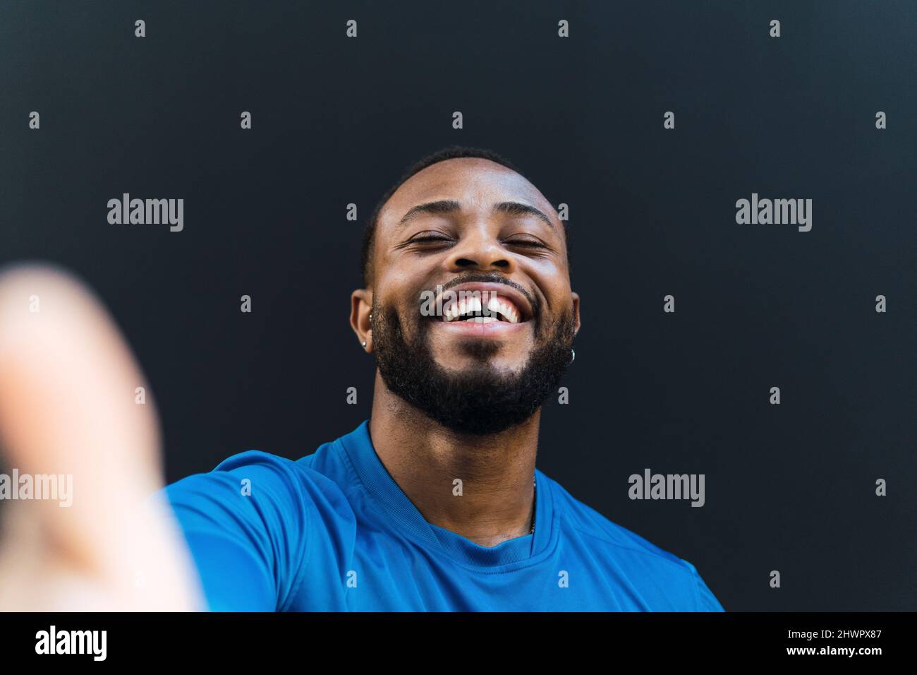 Un atleta allegro con denti vuoti che prendono selfie su sfondo nero Foto Stock