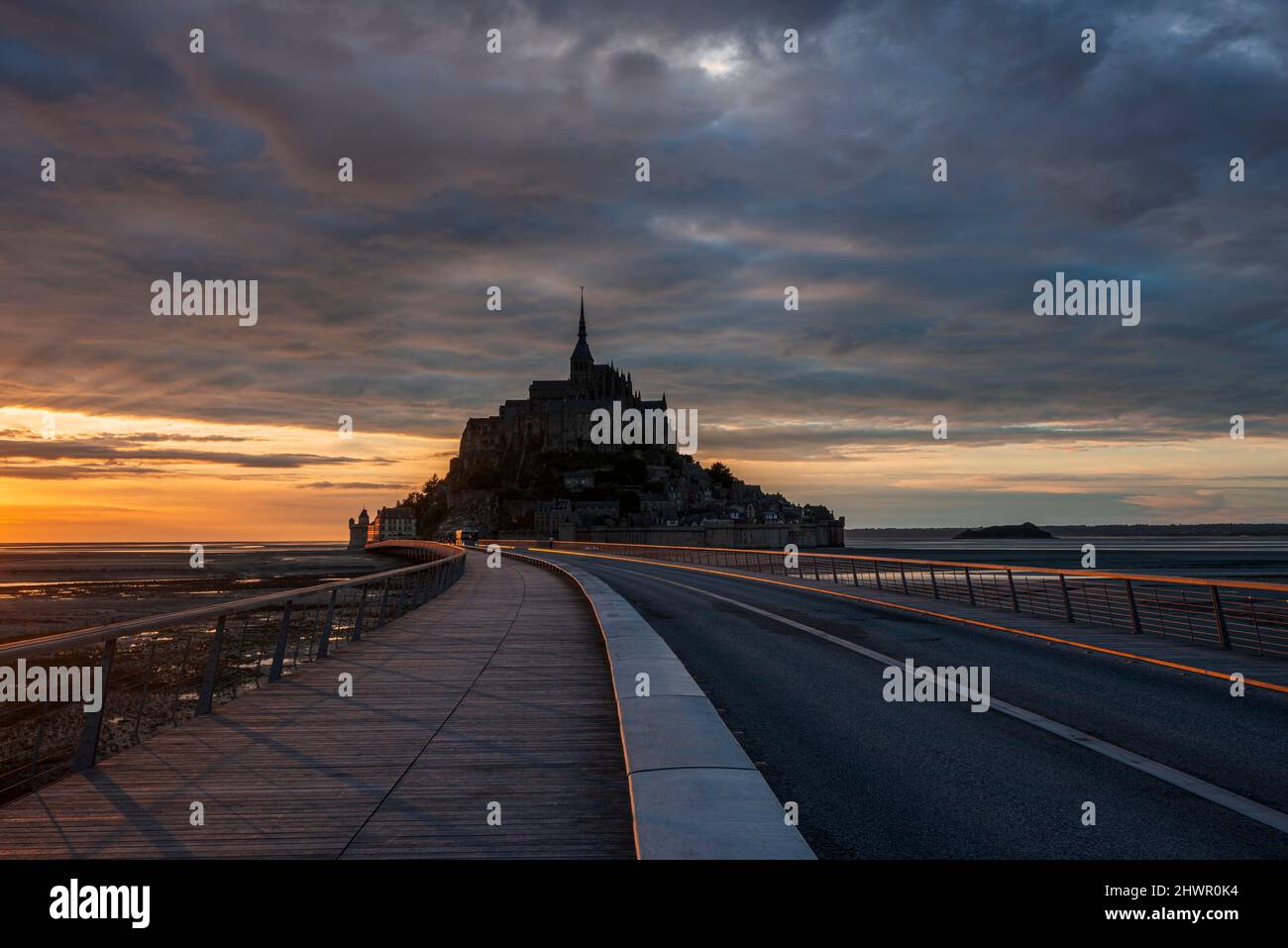 Francia, Normandia, cielo nuvoloso sul ponte che collega Mont-Saint-Michel isola al crepuscolo Foto Stock