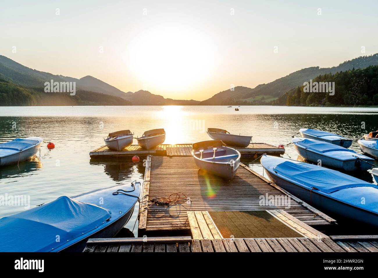 Barche ormeggiate lungo il molo sulla riva del lago Fuschl al tramonto Foto Stock