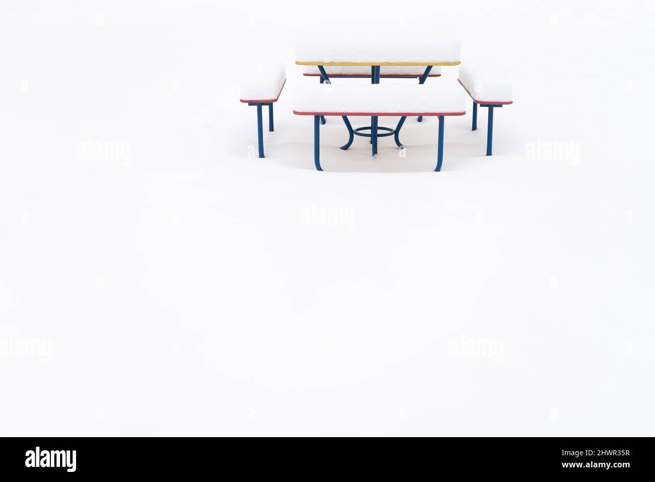 Panca vuota e tavolo coperto di neve nel parco pubblico Foto Stock