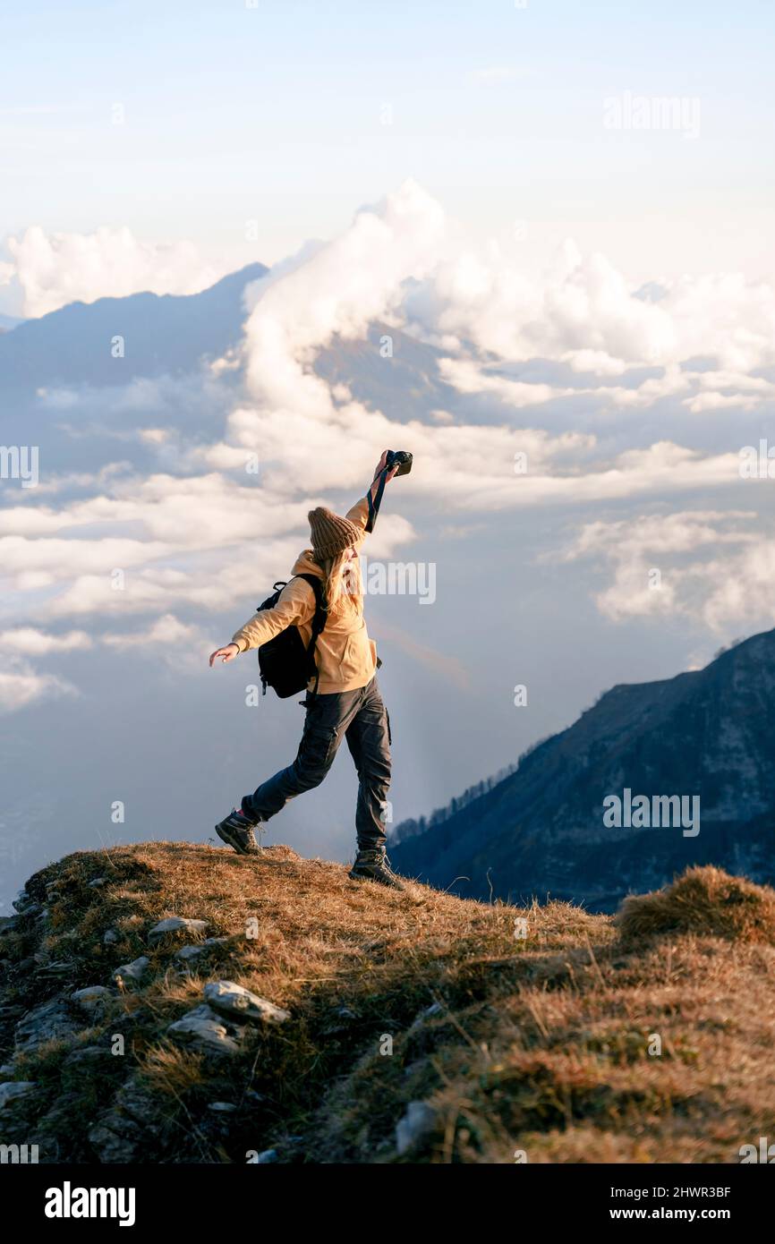 Donna con le braccia distese che cammina sul bordo della montagna nella Riserva Naturale del Caucaso a Sochi, Russia Foto Stock