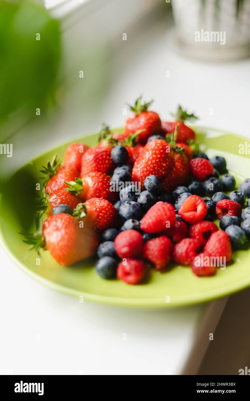 Piatto di mirtilli, lamponi e fragole su tavola Foto Stock