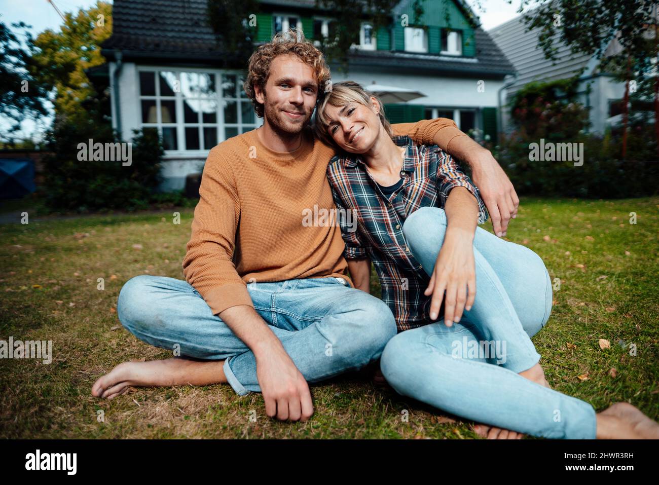 Coppia seduta insieme a terra in giardino Foto Stock