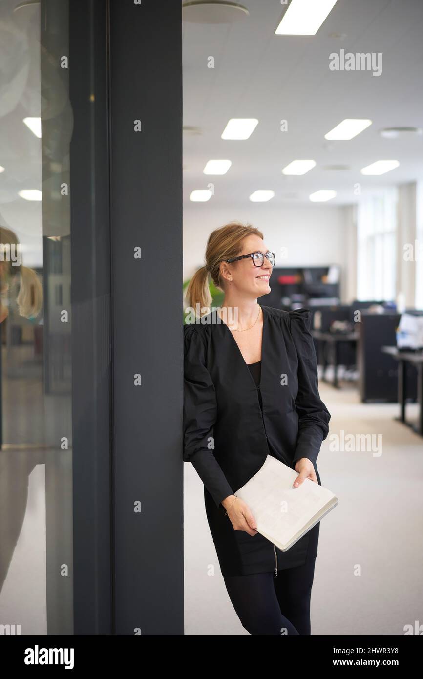 Donna d'affari contemplativa con documento in ufficio Foto Stock