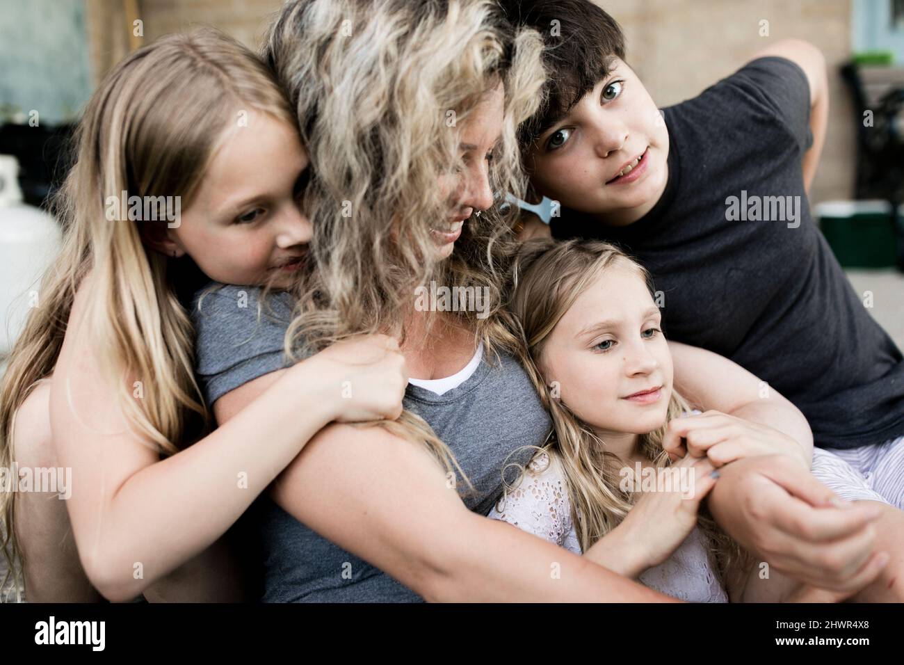 Madre sorridente seduta con figlio e figlie Foto Stock