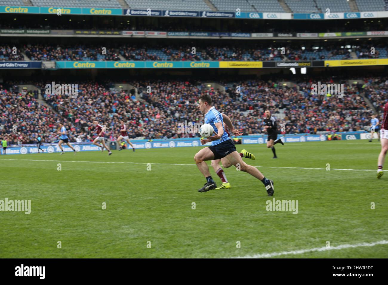 Una scena di una partita di calcio gaelica a Dublino, in Irlanda, come giocatore di Dublino porta la palla in avanti. Foto Stock