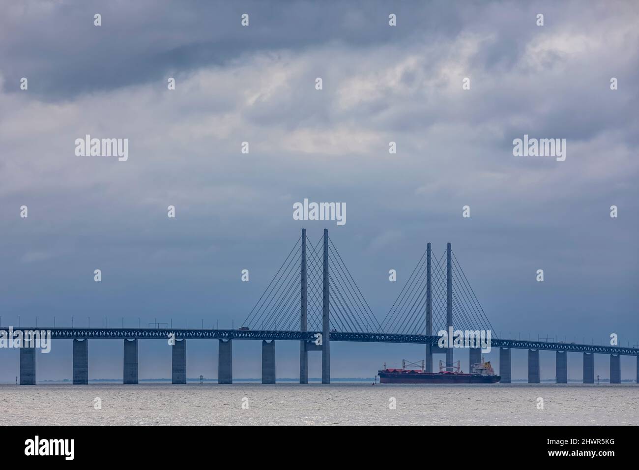 Cielo nuvoloso su nave container che naviga sotto il ponte Oresund Foto Stock