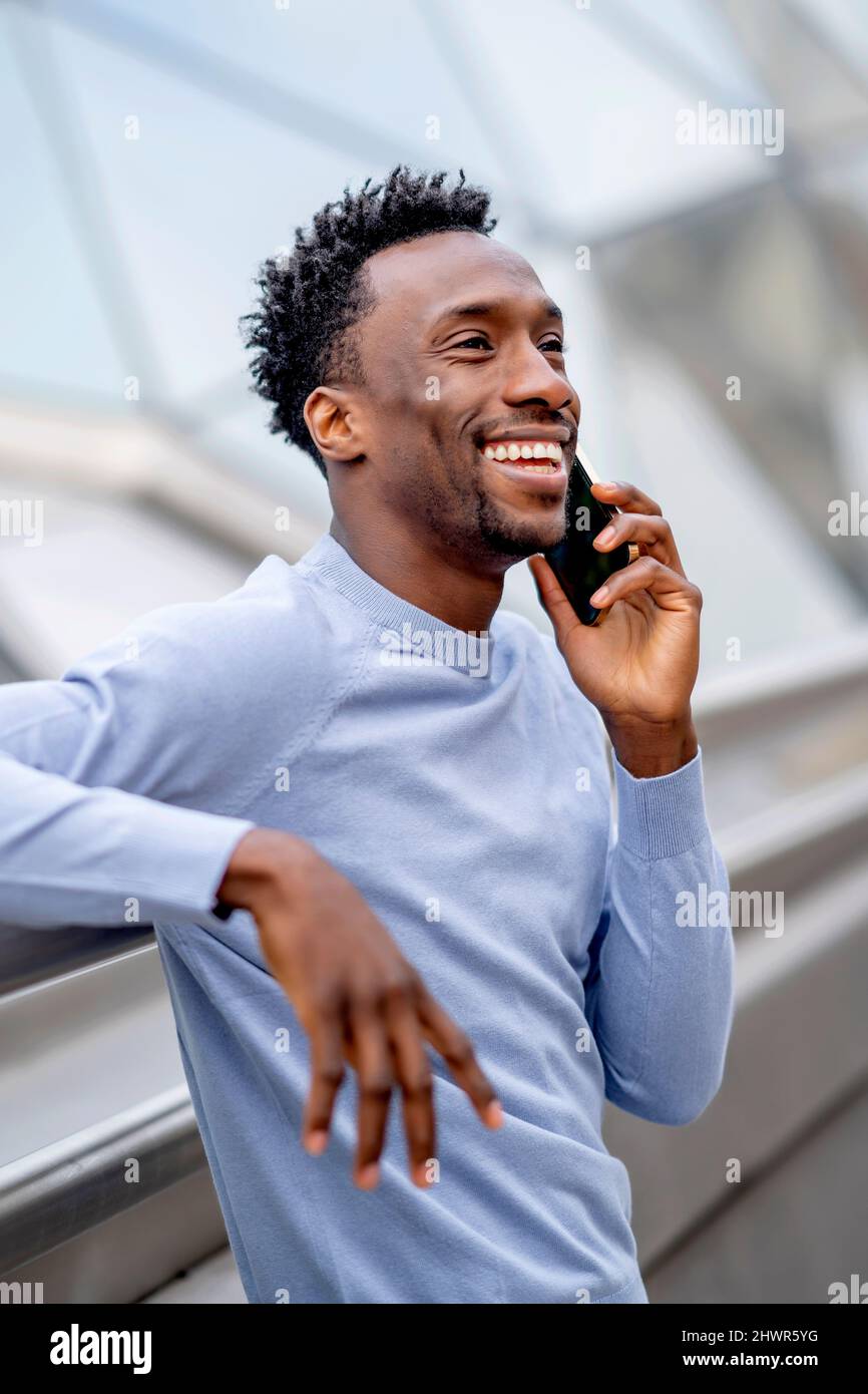 Uomo felice con i capelli neri che parlano sullo smartphone Foto Stock
